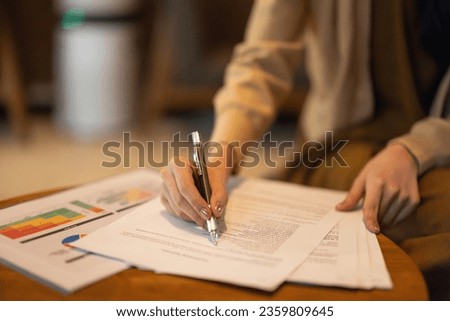 Asian female executive do a comprehensive analysis while situated in a coffee shop, granting remote approval for a prospective investment project. Carefully devised strategic decision for expansion. Royalty-Free Stock Photo #2359809645