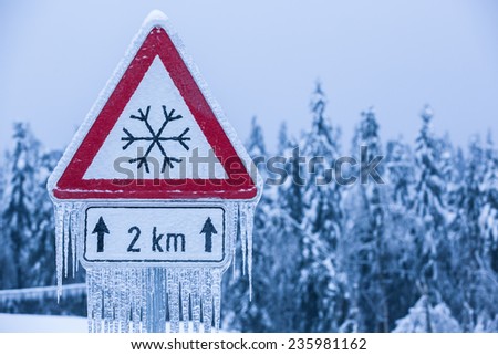 Traffic sign for icy road with sleet covered trees
