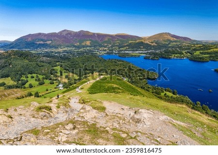 Hikers ascending a ridge overlooking a large lake (Catbells and Keswick, Cumbria) Royalty-Free Stock Photo #2359816475