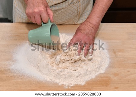 grandmother pours liquid yeast on dough at home
