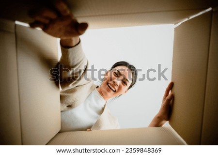 Surprised young asian woman unpacking. Opening carton box and looking inside. Packaging box, delivery service. Human emotions and facial expression Royalty-Free Stock Photo #2359848369