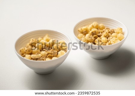 Breakfast cereal with granola and corn rings in small bowls on a white background
