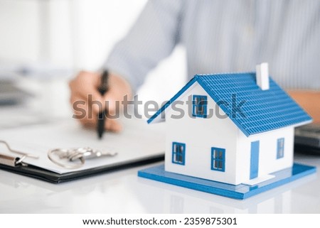 Model houses and contract documents on the desk in the office to decide to sign a home insurance contract about mortgage and home insurance offers