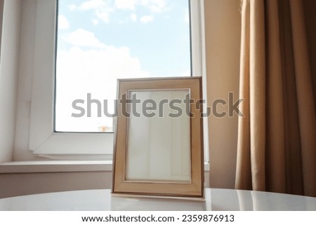 Beautiful empty photo frame near window can be used for mockup