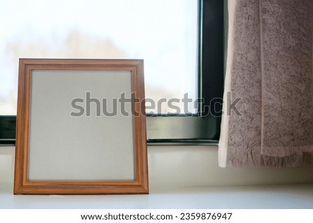 Beautiful empty photo frame near window can be used for mockup