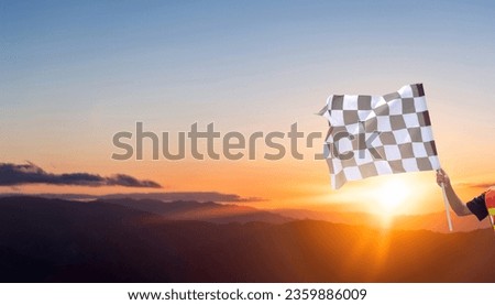 Checkered race flag in hand against sunset sky Royalty-Free Stock Photo #2359886009
