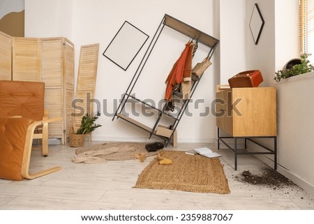 Chest of drawers and rack with clothes in messy room Royalty-Free Stock Photo #2359887067