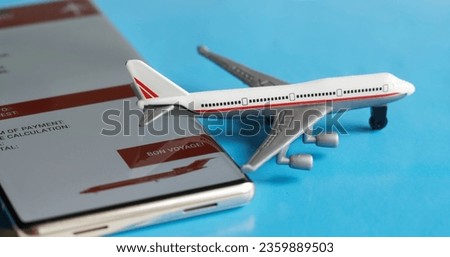 A toy passenger airliner next to a mobile phone - a smartphone with an electronic air ticket form. The concept of buying and using an electronic air ticket for travel. Photo. Macro. Close-up