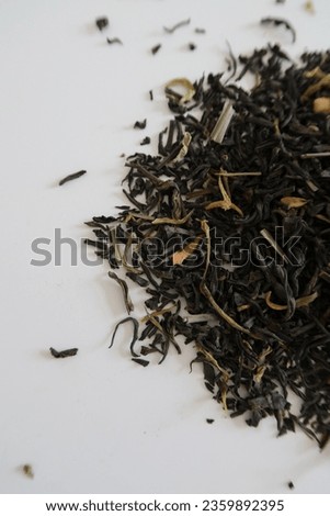 Closeup image of a pile of dry black tea leaves on a white table, focused picture of tea leafs, minimalistic white home aesthetics, no people, details of tea, healthy lifestyle, calm morning mood