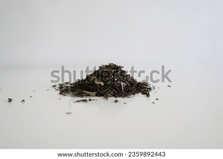Closeup image of a pile of dry black tea leaves on a white table, focused picture of tea leafs, minimalistic white home aesthetics, no people, details of tea, healthy lifestyle, calm morning mood