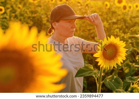 Female farmer with trucker's hat in blooming sunflower field. Agriculture and farming concept. Selective focus. Royalty-Free Stock Photo #2359894477