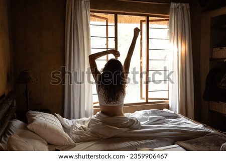 Young woman doing morning stretches in bed after wake-up Royalty-Free Stock Photo #2359906467