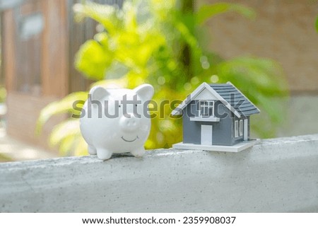 piggybank and the home model stands in front of home background, Saving money for buy real Estate concept.