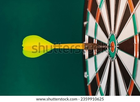 Dart sticks to bullseye on a dart board Royalty-Free Stock Photo #2359910625