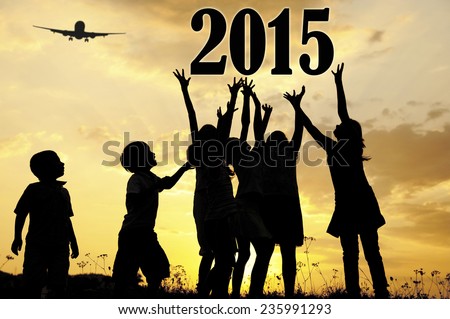 Silhouette of children running and jumping on the summer sunset meadow for happy new 2015 year