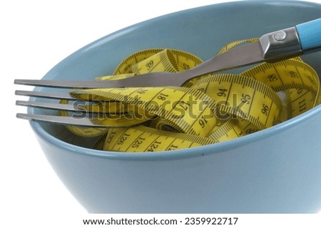 Diet concept with flexible measuring stick and fork in bowl close-up on white background Royalty-Free Stock Photo #2359922717