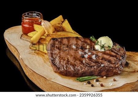 A piece of steak seared on the barbecue  on top with herb butter with french fries on cutting board
