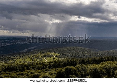 Sun rays shining through rainclouds showing thefalling rain in Northern Israel looking towards the Mediterranean Sea from Muhraqa viewpoint.
 Royalty-Free Stock Photo #2359945831