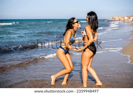 Two pretty young woman having fun on the seaside at hot summer day