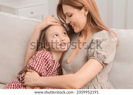 Mother and her cute daughter on sofa at home
