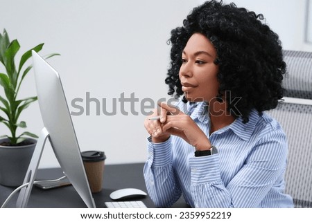 Young woman working on computer at table in office