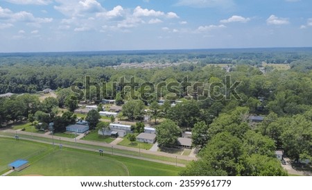 Large baseball fields near row of manufactured, modular, and mobile homes in Richland, Rankin County, Mississippi suburb of Jackson, lush green trees neighborhood. Aerial view affordable housing