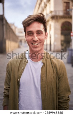 Vertical close up portrait of happy young European man happy smiling face on street. Male people with cheerful expression looking at camera in open air. Nice boy posing for photo outdoor.  Royalty-Free Stock Photo #2359965565
