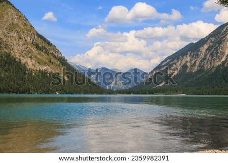 View over the lake Heiterwanger See near Heiterwang in Austria on a sunny day with blue sky and cumulus clouds. Royalty-Free Stock Photo #2359982391