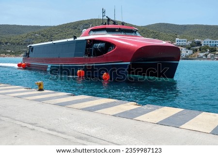 Fast Ferry reaches Megalochori, Milos, Miloi port, Greece, Agistri island. Public transport for summer holiday, calm sea, blue sky background. Royalty-Free Stock Photo #2359987123