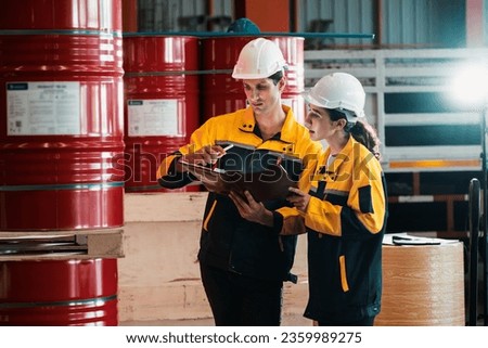 Two factory workers or inventory inspector conduct professional inspection on hazardous chemical barrels in warehouse, chemistry storage workplace and industrial profession concept. Exemplifying Royalty-Free Stock Photo #2359989275
