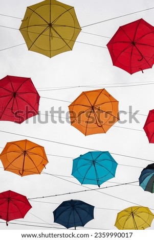 multi-colored umbrellas hang against the background of a white sky