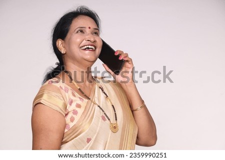 Indian happy women talking mobile phone. wearing traditional colorful golden saree. isolated over white studio background.