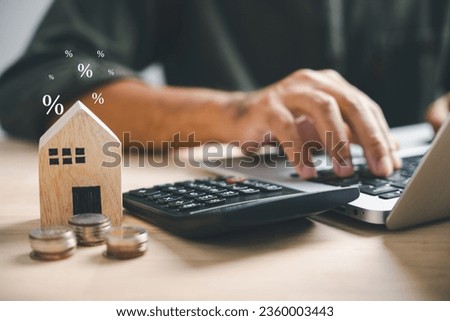 Pressing calculators, hand plans home refinance. House model, buy or rent, calculators on desk. Saving for property purchase, optimal mortgage payment. Tax, credit analysis for financial planning. Royalty-Free Stock Photo #2360003443
