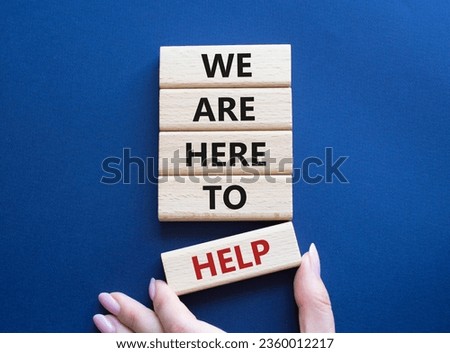 We are here to help symbol. Concept words we are here to help on wooden blocks. Beautiful deep blue background. Businessman hand. Business and we are here to help concept. Copy space. Royalty-Free Stock Photo #2360012217