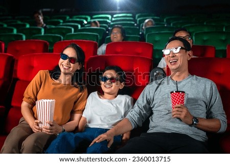 Asian family relax and fun togather by watching 3d action cinema in theater, father mother and daughter holiday in weekend with action movie
