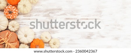 Autumn farmhouse pumpkin corner border over a white wood banner background. Rustic orange and white cloth pumpkins. Top down view with copy space.