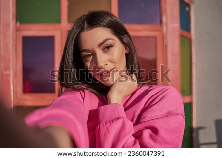 Lovely brunette girl making selfie at the summer street with vivid wall