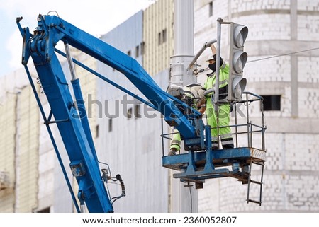 Worker team in uniform on aerial platform install new led traffic lights, new traffic signal. Traffic lights repair works, workers in lift bucket working at height. Installing  traffic signals on pole