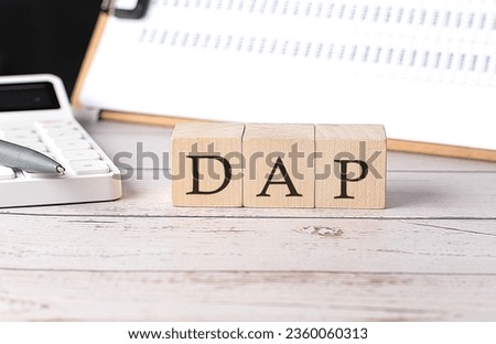 DAP word on wooden block with clipboard and calculator