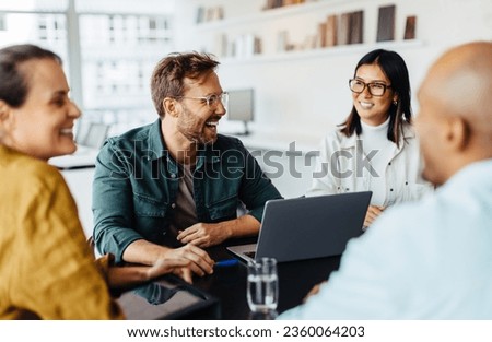 Diverse business people having a team meeting in an office. Group of happy business professionals sitting around a table and having a discussion. Royalty-Free Stock Photo #2360064203