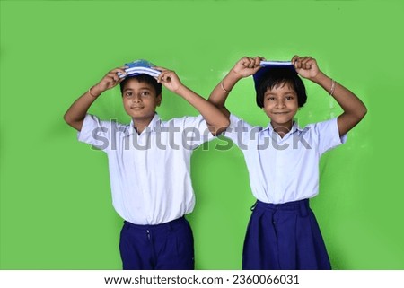 Smiling boy  and girl holding stack of books on head