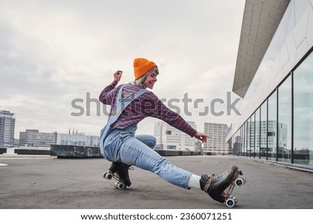 Full body portrait of positive funky woman learning to ride on roller skates Royalty-Free Stock Photo #2360071251