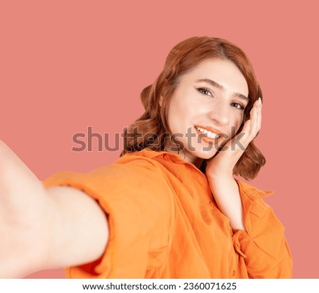 Taking selfie, close up portrait of young woman taking selfie. Caucasian girl taking pictures by her mobile phone smartphone Smiling, happy, fun, positive red bob hair lady touching her face gently.