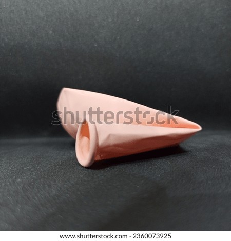 image of a pink balloon that has not yet been blown up on a black background