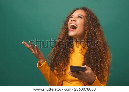 Young biracial woman celebrates after reading text wow, green studio background