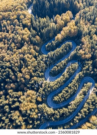 Aerial panoramic view of amazing curved road through the mountains, during an autumn sunrise