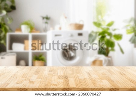 Empty wooden board with towels on blurred background of washing machine in home laundry. Place for product mounting and advertising