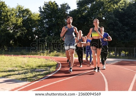 Group of people running at stadium on sunny day. Space for text Royalty-Free Stock Photo #2360094569
