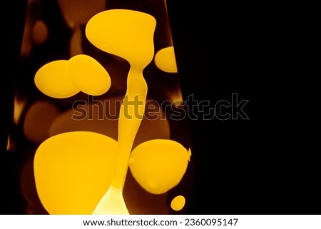 Yellow lava lamp, black background, horizontal format with copy space