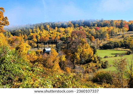 Old barn amongst hills of colorful autumn leaves in the countryside near Woodstock, Vermont, USA